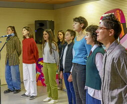 Maite Arroitajauregi musikaria, lehen planoan, berak sortutako pieza abesten duten gazteekin batera.