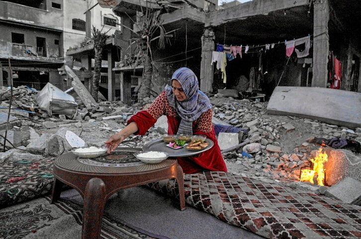 Una palestina prepara la cena que rompe el ayuno entre las ruinas de su casa en Deir el-Balah.