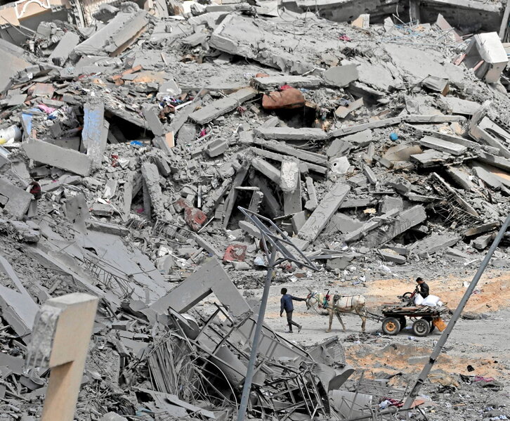 Palestinarrak, suntsitutako etxeen hondakinen artean, Khan Yunisen.