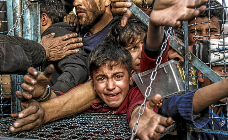 Niños palestinos esperan un reparto de comida en el campamento de refugiados de Yabalia.