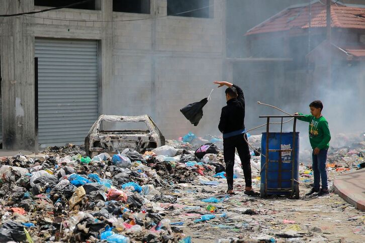 Un niño arroja una bolsa de basura en una calle de la ciudad de Gaza.