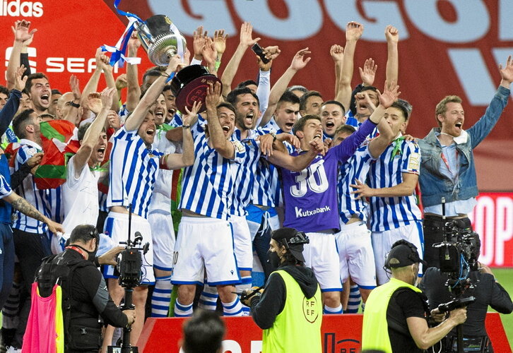 Ezkerrean, Realeko jokalariak Kopako garaipena ospatzen 2021ean. Eskuinean, Athleticeko zaleak Bilboko Plaza Berrian.