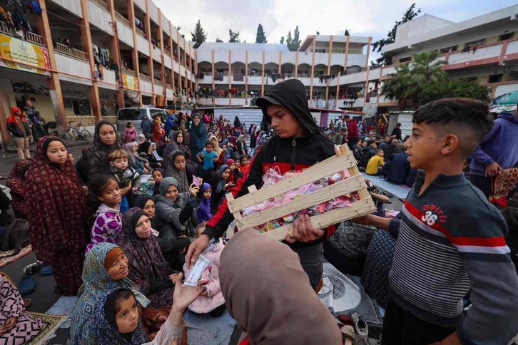 Un chico reparte dulces entre los niños desplazados en una escuela convertida en refugio en Rafah.