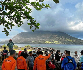 Equipos de rescate junto a civiles observan el volcán Ruang.