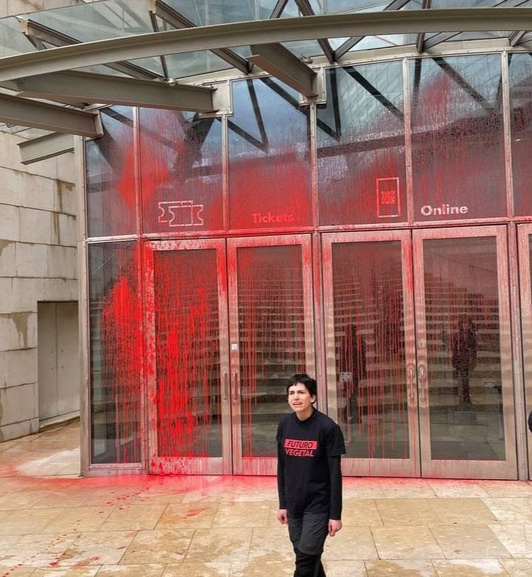 Activista de Futuro Vegetal junto a la entrada del Museo Guggenheim con pintura en la fachada.