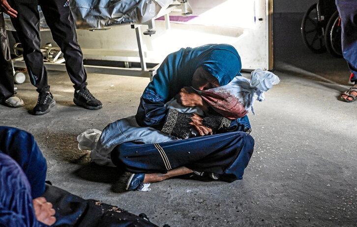 Una mujer palestina abraza el cuerpo amortajado de niño al que Israel mató en un bombardeo sobre Rafah.