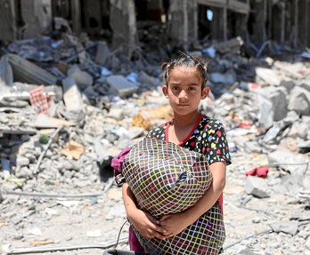 Una niña con pertenencias que ha salvado a su regreso al destruido campo de Yabalia.