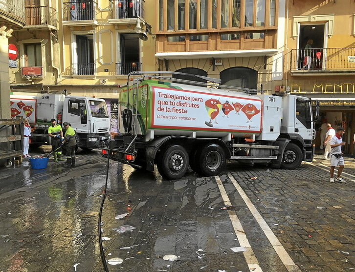 Dos camiones de la limpieza, en pleno recorrido del encierro tras la carrera.