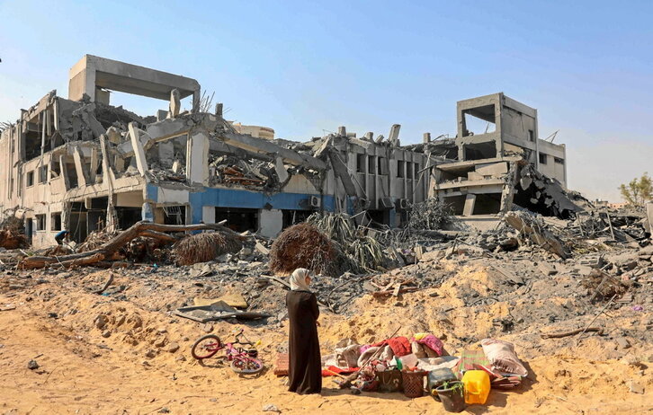 Una mujer aguarda con algunos artículos rescatados del bombardeado complejo de la Unrwa en la ciudad de Gaza.