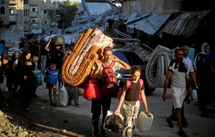Palestinos abandonan el campo de refugiados de Al-Bureij con sus pocas pertenencias en su enésimo desplazamiento.