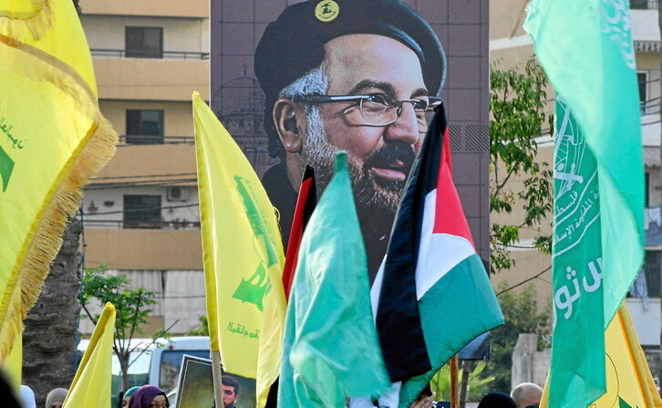 Banderas de Palestina y de Hezbolá frente a un gran retrato de Fuad Shukr, comandante de la milicia muerto por Israel.