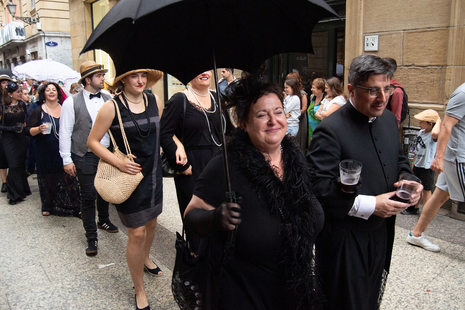 Emakume bat, beltzez, errespetu osoz apaiz bati besotik helduta. Emakume bat, beltzez, errespetu osoz apaiz bati besotik helduta.