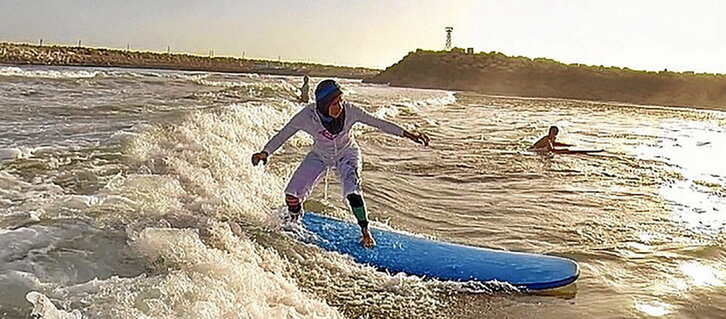 Lerro hauen alboan, Shahla Yasini, surf taularekin; bigarren orrialdean, goian, surflariak itsasertzean, eta behean, olatuak hartzen.