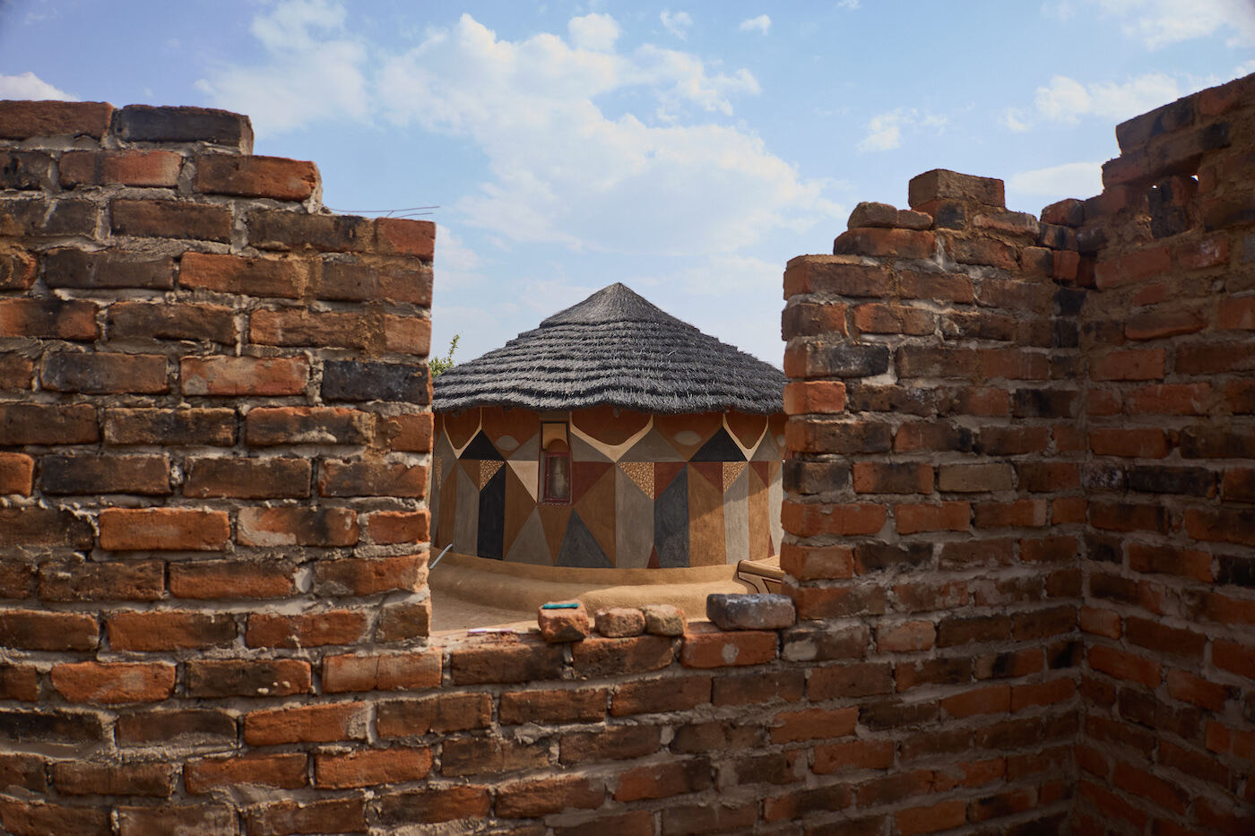 Panorámica de una cabaña pintada a través de una ventana de otra en construcción, en Matobo. (Z. AUNTONY | AFP)