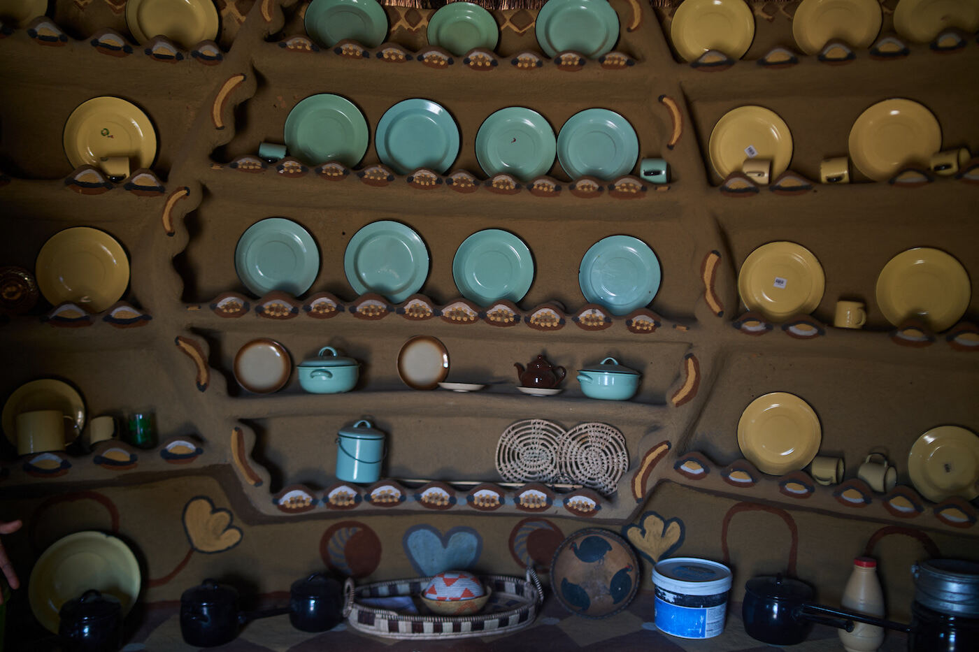 Platos y utensilios colocados decorativamente dentro de una cocina pintada con barro. (Z. AUNTONY | AFP)