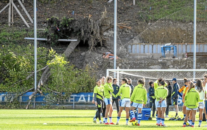Jugadoras en el césped de Zubieta y al fondo, un arbol derribado por el viento.