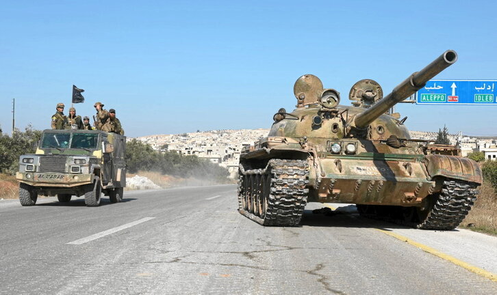 Yihadistas pasan junto a un tanque abandonado por el Ejército en la carretera que lleva de Alepo a Hama.