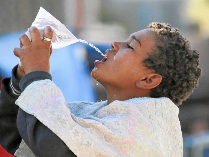 Un niño bebe agua de una bolsa en Jan Yunis.