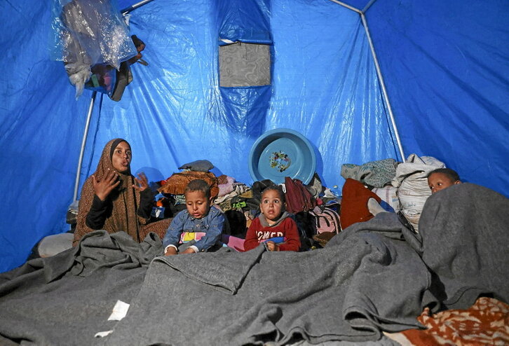 Una mujer, junto a varios niños en una tienda de campaña en Jan Yunis.