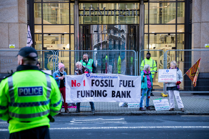 Activistas del movimiento Extinción Rebelión sostienen una pancarta frente al banco estadounidense JPMorgan en Glasgow