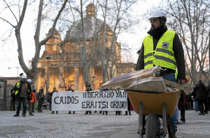 Un «obrero» transporta una carretilla con escombros, formando parte de un grupo de demolición improvisado.