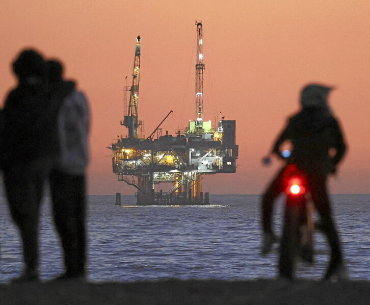 En la página anterior, la plataforma petrolera y de gas Esther, frente a Seal Beach (California). Al lado, Trump habla por videoconferencia en Davos.