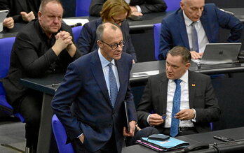 Friedrich Merz, líder de la CDU, pasa junto a Tino Chrupalla, colíder del partido neofascista AfD, a su llegada a la sesión en el Bundestag.