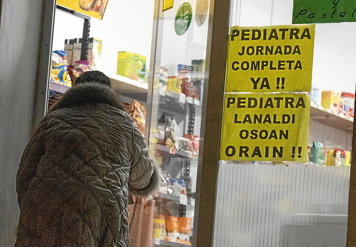 Sobre estas líneas, un cartel reclama un pediatra a jornada completa en un comercio de San Miguel. En la página siguiente Javier Collado y Txutxi Villaverde, de la Asociación de Vecinos de San Miguel.