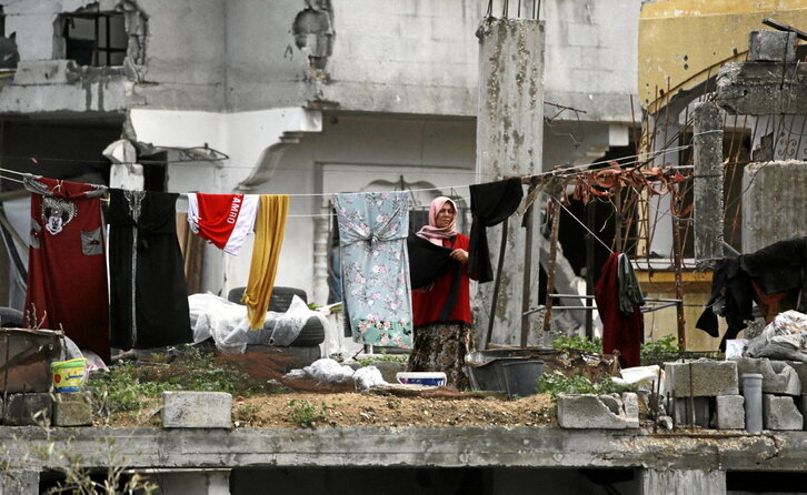 Una mujer tiende la ropa en un edificio semidestruido en Yabalia.