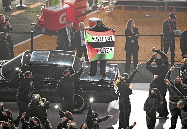 Boluntario ekintzailea, ikurra erakutsiz, Kendrick Lamarren emanaldiaren erdian.