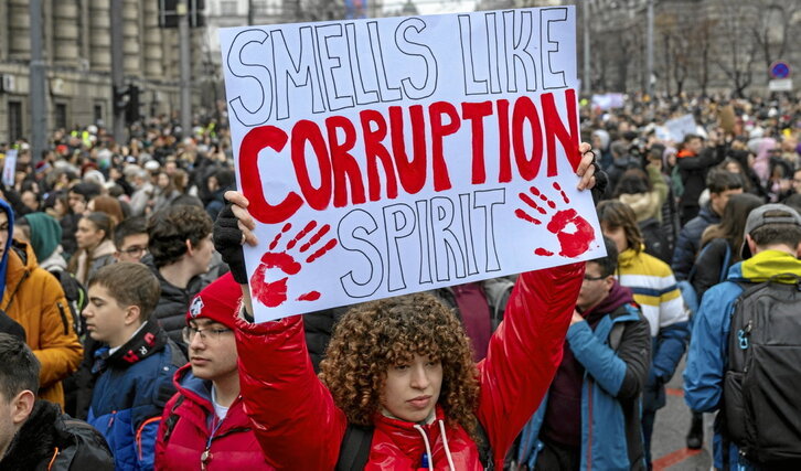 Una joven muestra un cartel contra la corrupción durante una protesta en Belgrado.