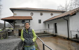 Jasone Mitxeltorena, Zubietako errotaren atarian. Euria galanki bota du eta putzua bete-betea ageri da.