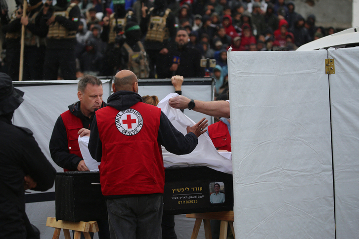 Miembros de la Cruz Roja cubren con una sábana blanca el ataúd con los restos de uno de los israelíes.