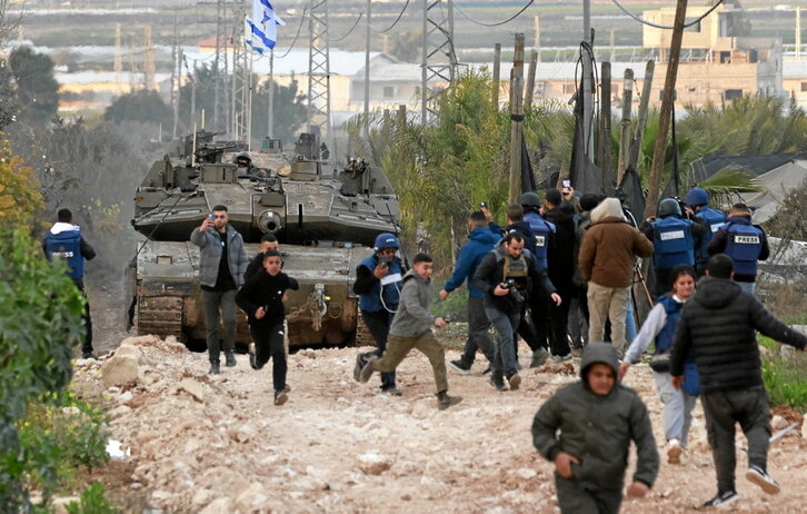 Palestinos y periodistas se dispersan ante la entrada de una columna de tanques en el campo de Jenin.