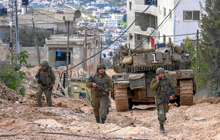 Soldados israelíes caminan delante de un tanque en el campo de refugiados de Jenin.