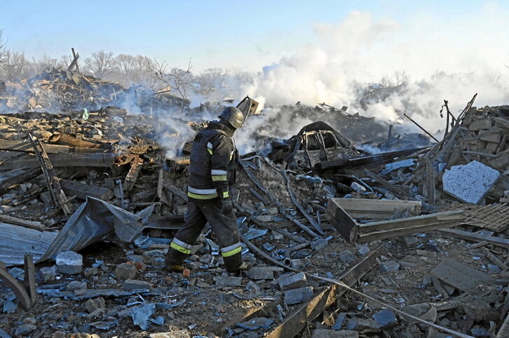 Ukrainar suhiltzaile batek misil batek suntsitutako eraikin bat arakatzen dihardu.