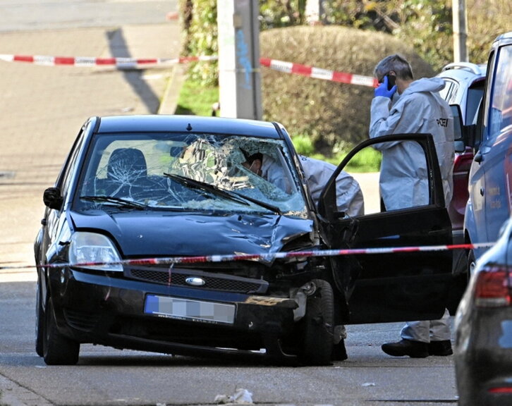 Policías investigan un coche dañado.