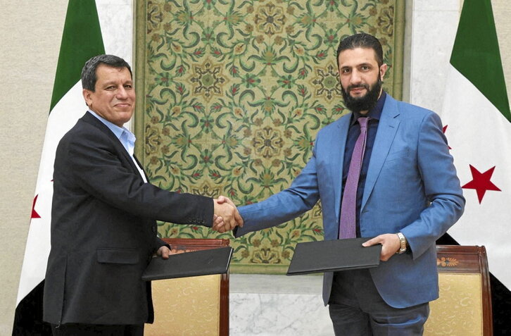 El presidente interino sirio, Ahmed al-Sharaa (d), y el comandante de las FDS, Mazloum Abdi (i), se dan la mano.