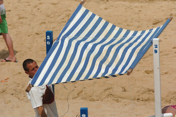 Un operario instala un toldo en la playa de La Concha.