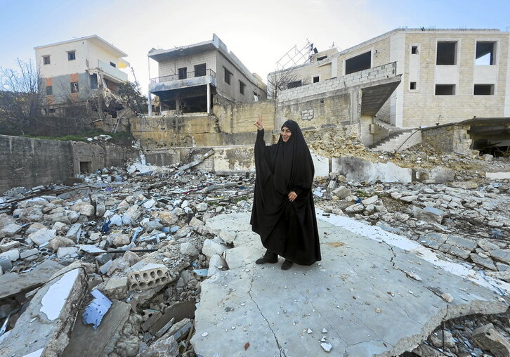 En la página anterior, una mujer hace el signo de la victoria dirigido a los soldados israelíes que vigilan con binoculares. Sobre estas líneas, varios hombres, sentados en un edificio en ruinas en Kfar Kila.