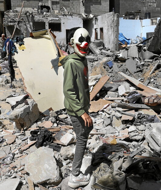 Un palestino con  la máscara de un payaso, entre los escombros en Gaza.