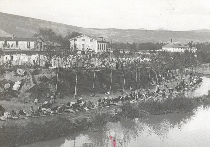 Grupo de modistas en un taller de trabajo de Iruñea hacia 1900. En la página anterior, lavanderas en plena faena en la orilla del río Arga en el año 1903.