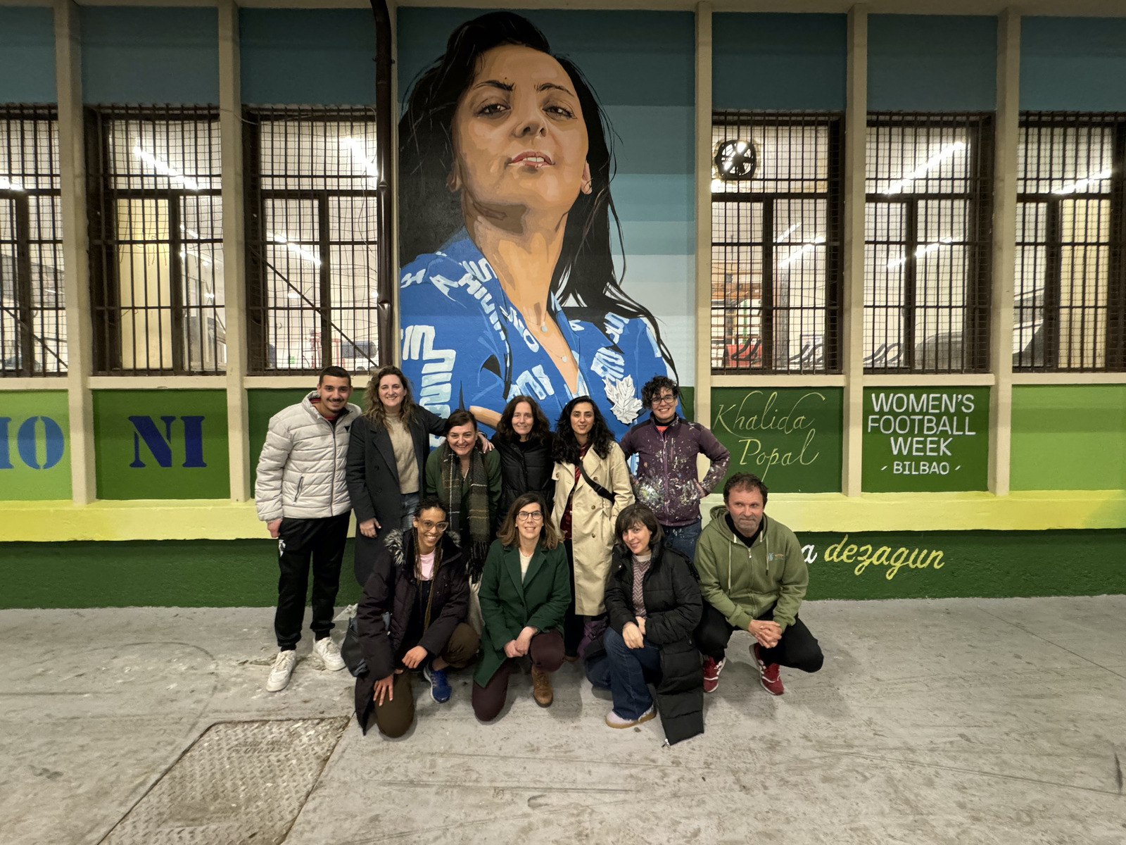 La activista afgana Khalida Popal posa junto a otros participantes en la Women’s Football Wekk ante el graffiti con su retrato que creó Eva Mena en Otxarkoaga. (WORLD FOOTBALL SUMMIT)