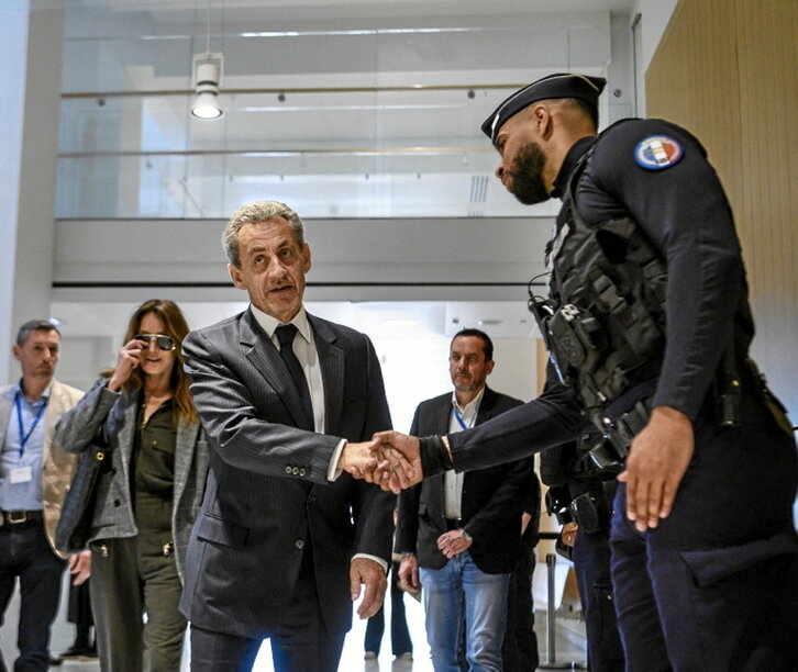 Sarkozy saluda a un policía a su llegada al tribunal.