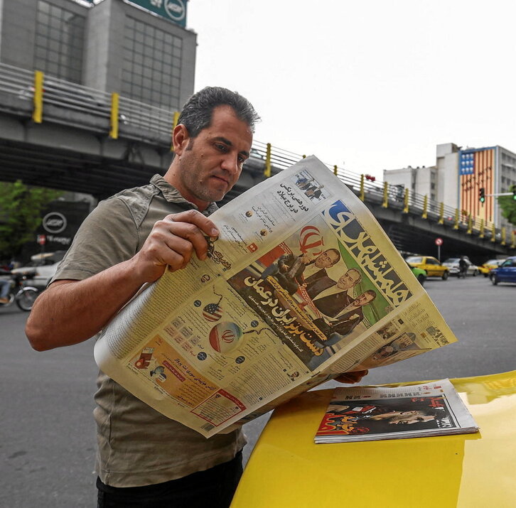 Un vecino de Teherán lee un periódico donde se informa de las negociaciones de Omán.