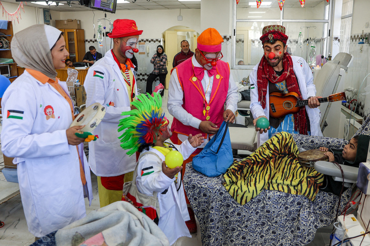 Un niño conectado a una máquina de diálisis toca una pandereta mientras miembros del equipo de la Escuela de Circo de Gaza actúan a su alrededor en el hospital Al-Rantisi.