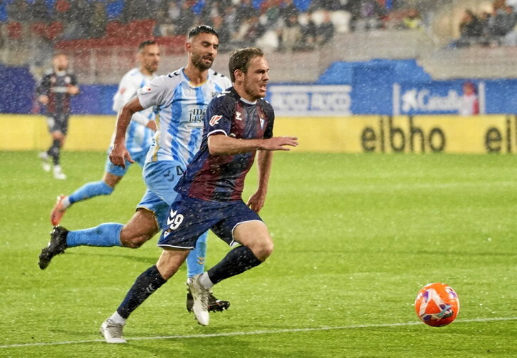 Bautista, autor del primer gol, corre bajo la intensa lluvia perseguido por Einar.