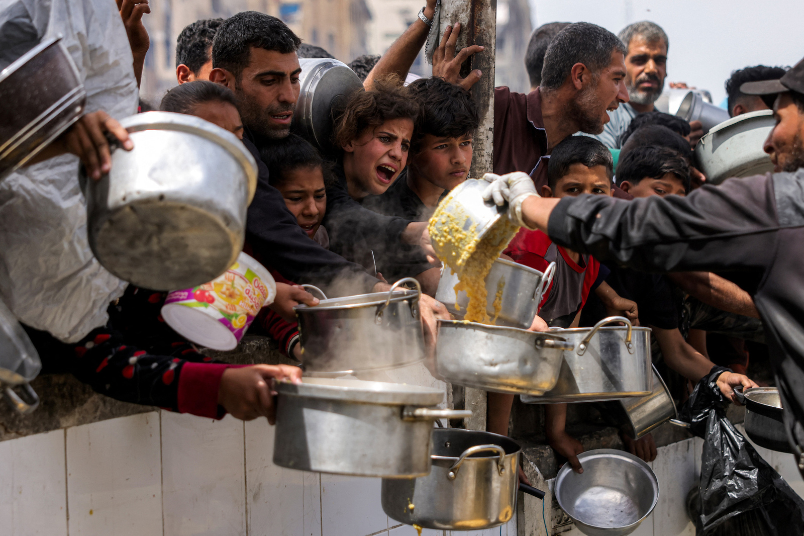 Palestinos tratan de hacerse con una ración de comida en Beit Lahia, en el norte de Gaza. (Bashar TALEB | AFP)