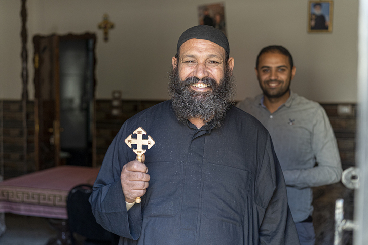 El sacerdote copto de Dayr Rifa, sonriente en su hogar.