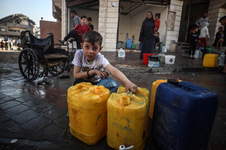 Un niño espera la llegada del agua en Gaza.